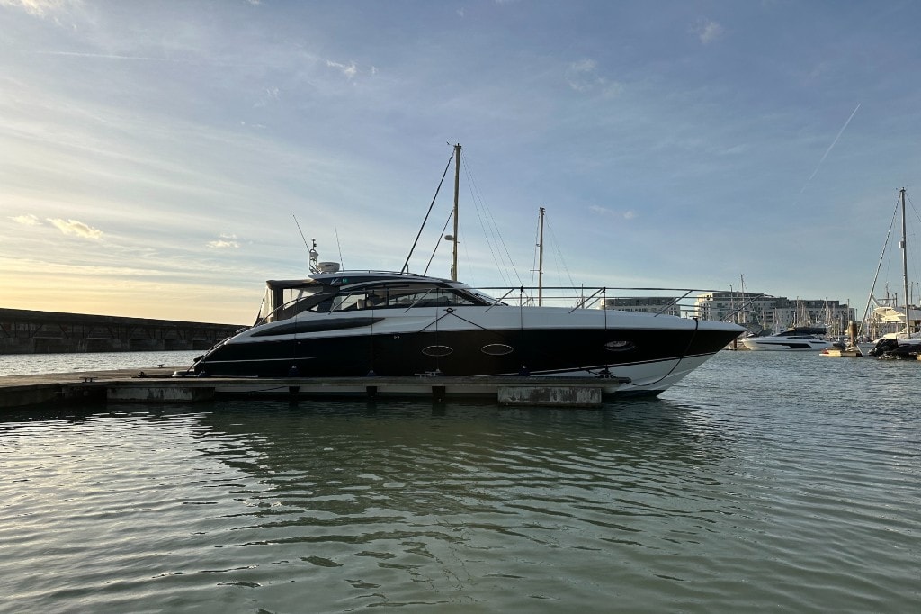 A dark-hulled motor yacht moored alongside a pontoon