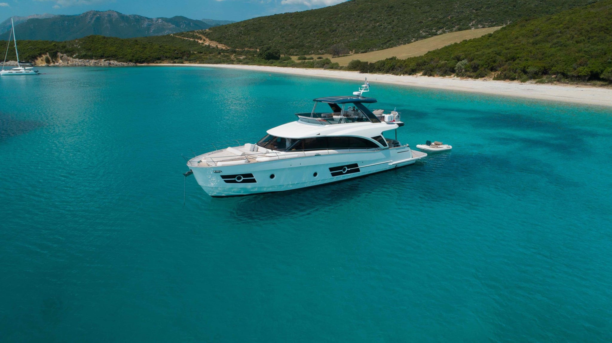 Motor yacht anchored in clear water beside a sandy bay